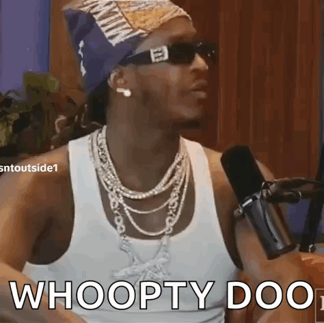 A Man Wearing Sunglasses And A Bandana Is Talking Into A Microphone . GIF