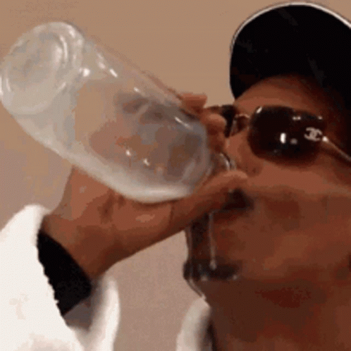 A Man Wearing Sunglasses And A Baseball Cap Is Drinking From A Bottle . GIF