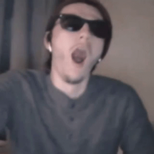 A Man Wearing Sunglasses And A Beanie Is Making A Funny Face GIF