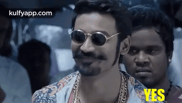 A Man Wearing Sunglasses And A Beard Is Smiling While Standing Next To Another Man . GIF