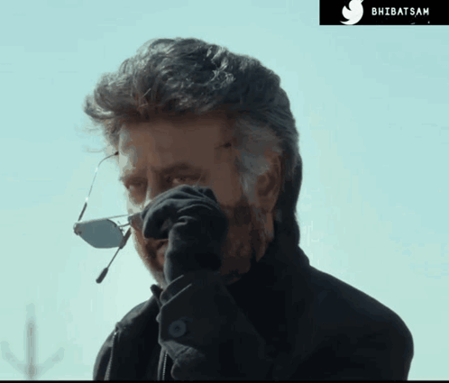 A Man Wearing Sunglasses And A Black Jacket Is Talking On A Cell Phone With A Twitter Logo In The Corner GIF