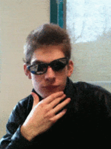 A Man Wearing Sunglasses And A Black Jacket Looks At The Camera GIF