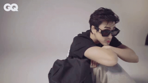 A Man Wearing Sunglasses And A Black Shirt With A Gq Logo On The Bottom GIF