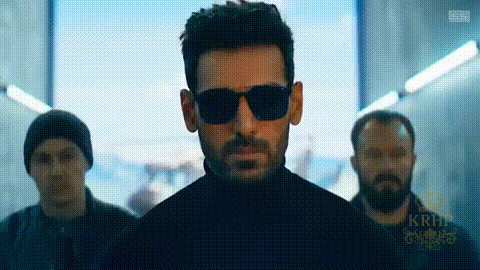 A Man Wearing Sunglasses And A Black Turtleneck Is Standing Next To Two Other Men . GIF