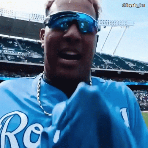 A Man Wearing Sunglasses And A Blue Royals Shirt GIF
