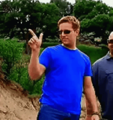 A Man Wearing Sunglasses And A Blue Shirt Is Pointing Up . GIF