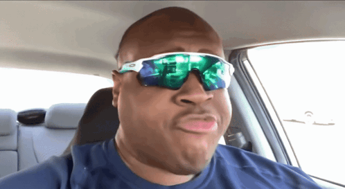 A Man Wearing Sunglasses And A Blue Shirt Making A Funny Face GIF
