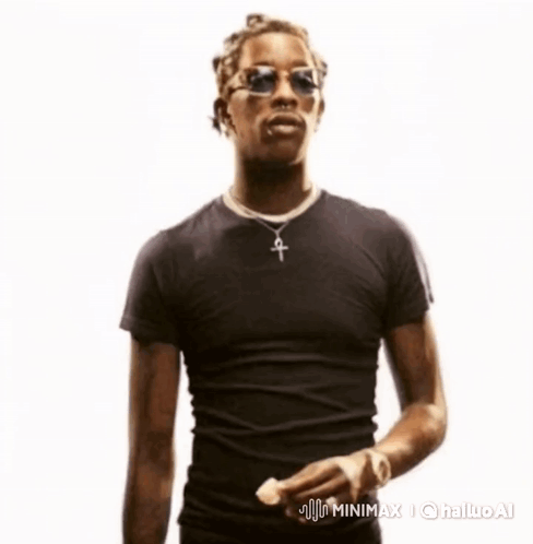 A Man Wearing Sunglasses And A Cross Necklace Is Standing In Front Of A White Background GIF