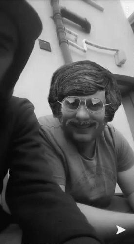 a man wearing sunglasses and a fake mustache is smiling