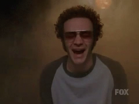 A Man Wearing Sunglasses And A Fox Shirt Is Screaming In A Dark Room . GIF