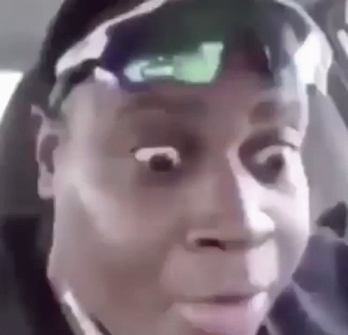 A Man Wearing Sunglasses And A Hat Is Making A Funny Face While Sitting In A Car . GIF