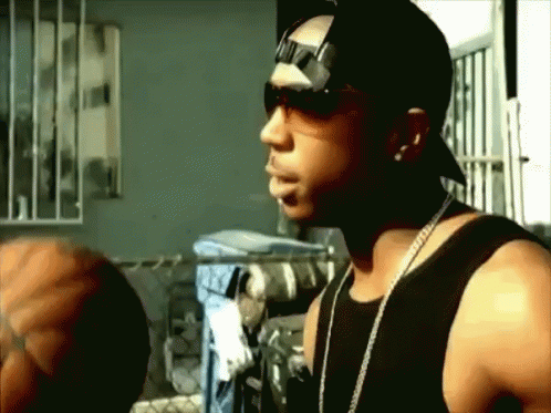 A Man Wearing Sunglasses And A Hat Is Standing In A Room GIF