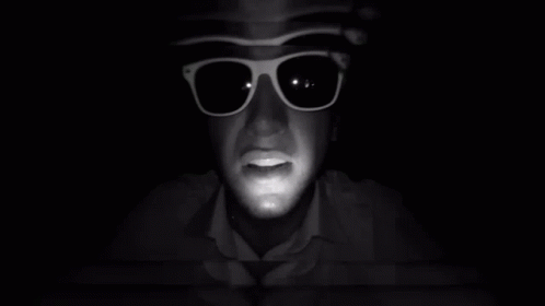 A Man Wearing Sunglasses And A Hat Looks At The Camera GIF