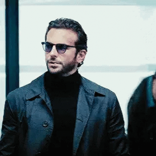 A Man Wearing Sunglasses And A Leather Jacket Is Standing Next To A Man Wearing A Turtleneck . GIF