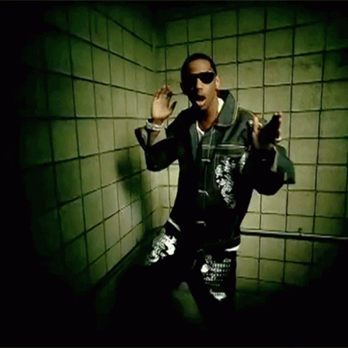 A Man Wearing Sunglasses And A Leather Jacket Stands In Front Of A Tiled Wall GIF