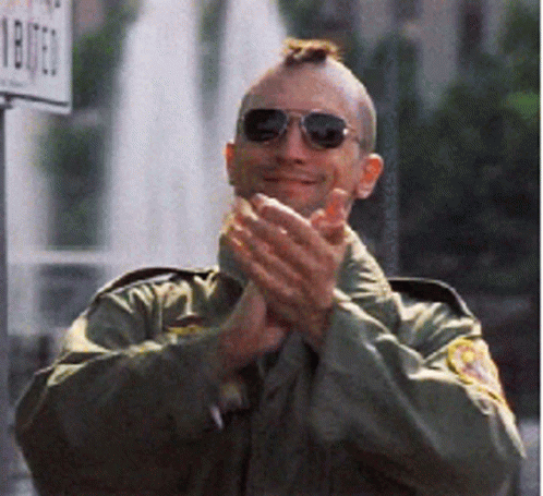 A Man Wearing Sunglasses And A Mohawk Applauds In Front Of A Sign That Says 1807 GIF