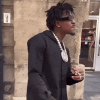 A Man Wearing Sunglasses And A Necklace Is Holding A Cup Of Coffee GIF