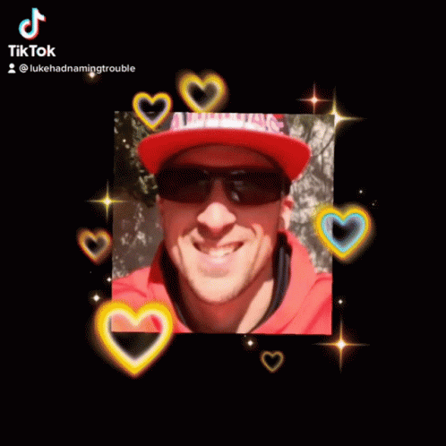 A Man Wearing Sunglasses And A Red Hat Is Smiling For The Camera GIF