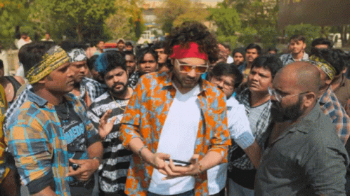 A Man Wearing Sunglasses And A Red Headband Is Surrounded By People GIF