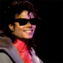 A Man Wearing Sunglasses And A Red Shirt Smiles GIF