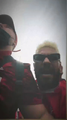 A Man Wearing Sunglasses And A Red Shirt With Adidas On It GIF