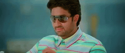 A Man Wearing Sunglasses And A Striped Shirt Is Sitting Down . GIF