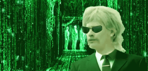 a man wearing sunglasses and a suit and tie is standing in front of a green background .
