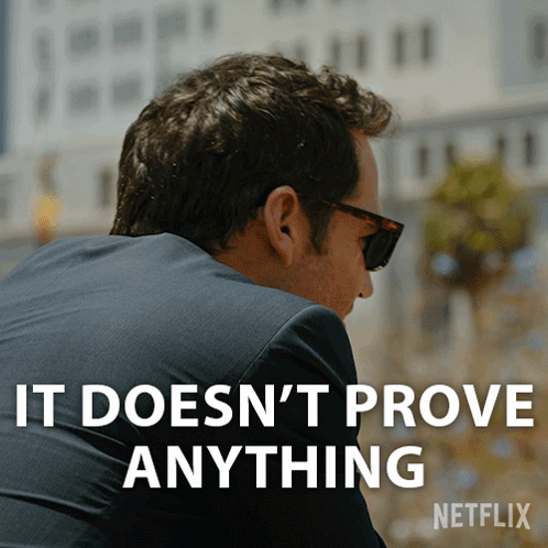 A Man Wearing Sunglasses And A Suit Has The Words " It Does N't Prove Anything " On His Back GIF