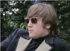 A Man Wearing Sunglasses And A Suit Is Sitting On A Chair . GIF