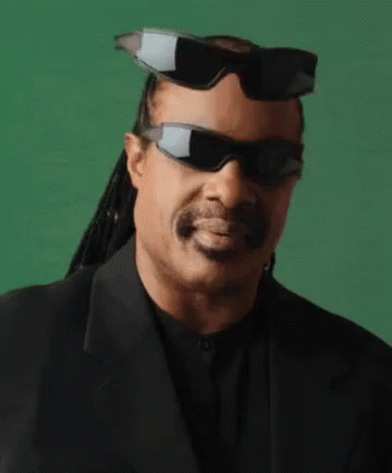 A Man Wearing Sunglasses And A Suit Is Smiling . GIF