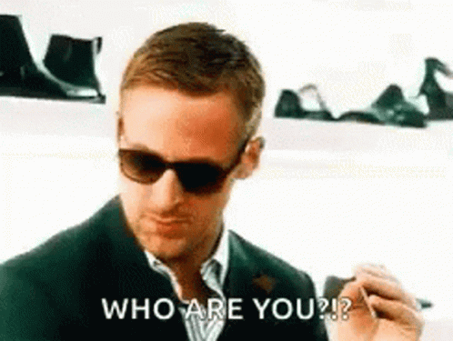 A Man Wearing Sunglasses And A Suit Is Smoking A Cigarette And Asking Who Are You ? GIF