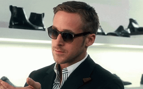 A Man Wearing Sunglasses And A Suit Is Standing In Front Of A Shoe Shelf GIF