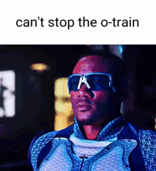 A Man Wearing Sunglasses And A Suit Is Standing In Front Of A Sign That Says Can 'T Stop The O-Train GIF