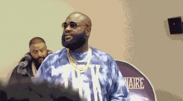 A Man Wearing Sunglasses And A Tie Dye Shirt Stands In Front Of A Sign That Says Aire . GIF