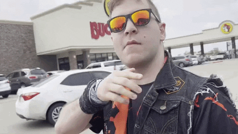 A Man Wearing Sunglasses And A Vest Is Standing In Front Of A Buck 'S Restaurant GIF