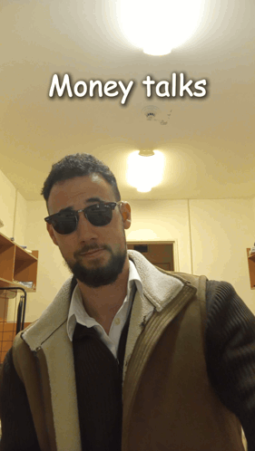 A Man Wearing Sunglasses And A Vest With The Words Money Talks Behind Him GIF