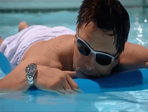 A Man Wearing Sunglasses And A Watch Is Laying In The Water GIF