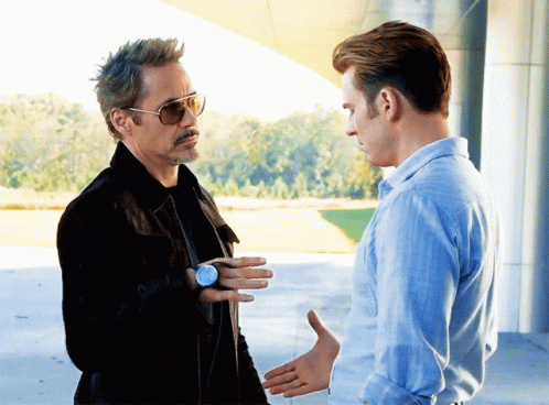 A Man Wearing Sunglasses And A Watch Talks To Another Man GIF