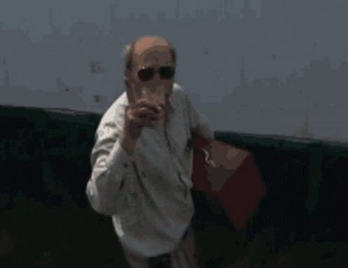 A Man Wearing Sunglasses And A White Shirt Holds A Red Bag GIF