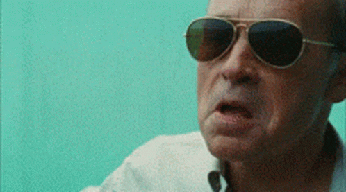 A Man Wearing Sunglasses And A White Shirt Is Making A Funny Face GIF