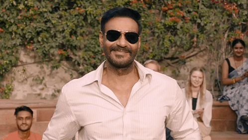 A Man Wearing Sunglasses And A White Shirt Is Smiling GIF
