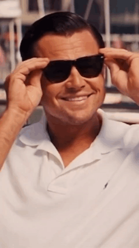 A Man Wearing Sunglasses And A White Shirt Smiles For The Camera GIF