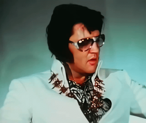 A Man Wearing Sunglasses And A White Shirt With Spikes On It GIF