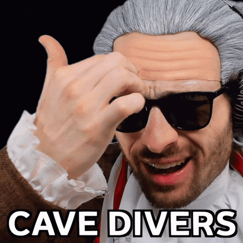 A Man Wearing Sunglasses And A Wig With The Words Cave Divers Above Him GIF