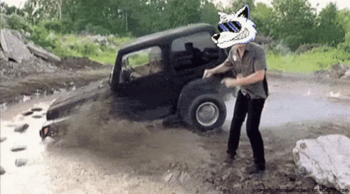 A Man Wearing Sunglasses And A Wolf Head Is Standing In Front Of A Jeep GIF
