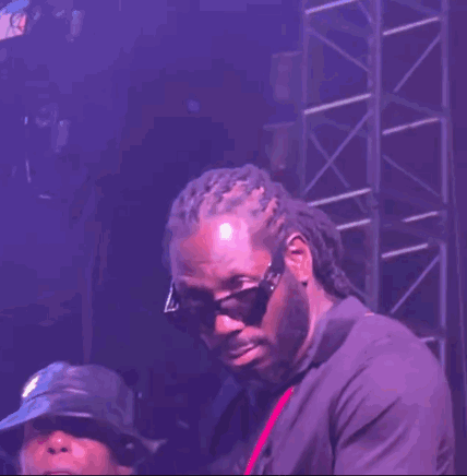 A Man Wearing Sunglasses And Dreadlocks Is Standing On A Stage GIF