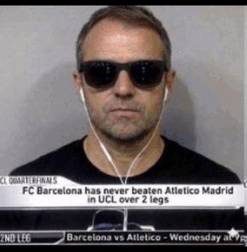 A Man Wearing Sunglasses And Ear Buds Is Standing In Front Of A Sign That Says Fc Barcelona GIF