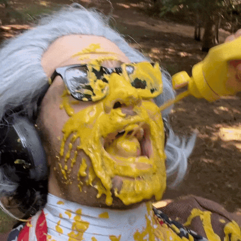 A Man Wearing Sunglasses And Headphones Is Covered In Yellow Liquid GIF