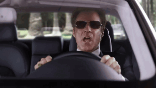 A Man Wearing Sunglasses Driving A Car With His Mouth Open GIF