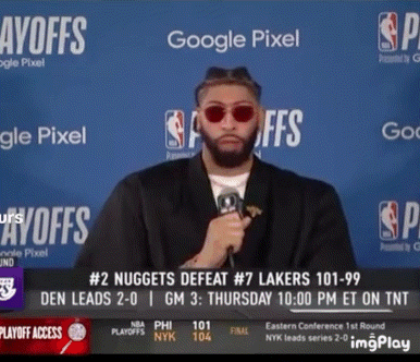 A Man Wearing Sunglasses Holds A Microphone In Front Of A Google Pixel Sign GIF